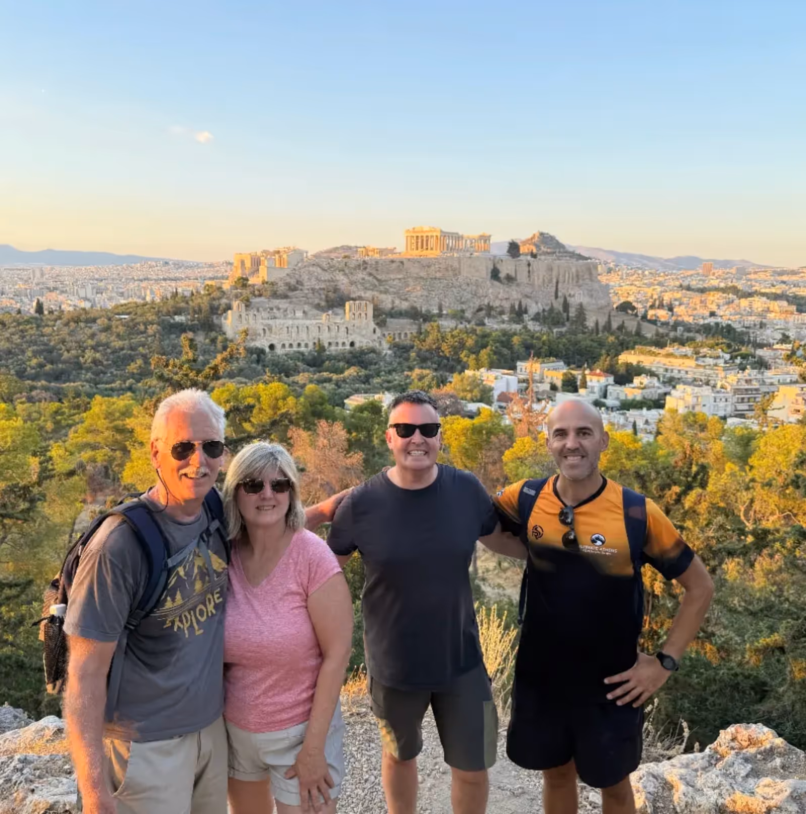 Small group of guests with their Athens tour leader, the Acropolis behind at golden hour